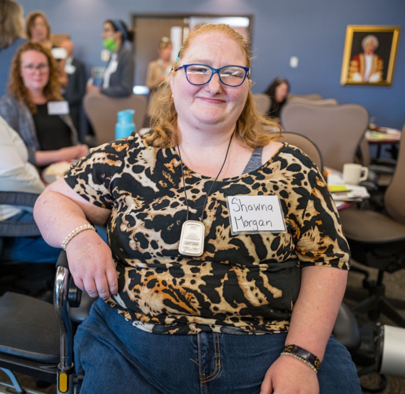 A white blond haired woman with glasses sitting and smiling at the Inclusive Housing Solutions Lab Forum in New Brunswick.