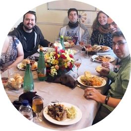 A group of 4 men and 1 woman seated together for a meal at a dining table.